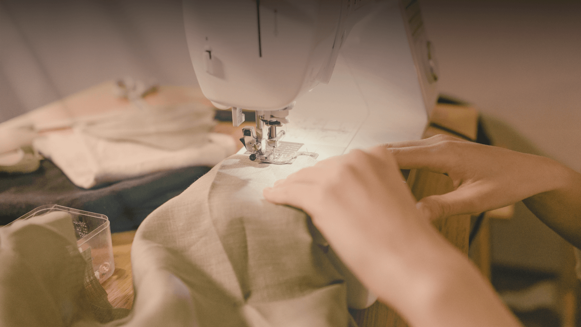 Hands guiding linen fabric through a sewing machine — crafted with care at Blush Boutique